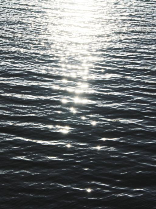 Nahaufnahme von Meerwasser auf denen die Lichtreflexe glitzern.