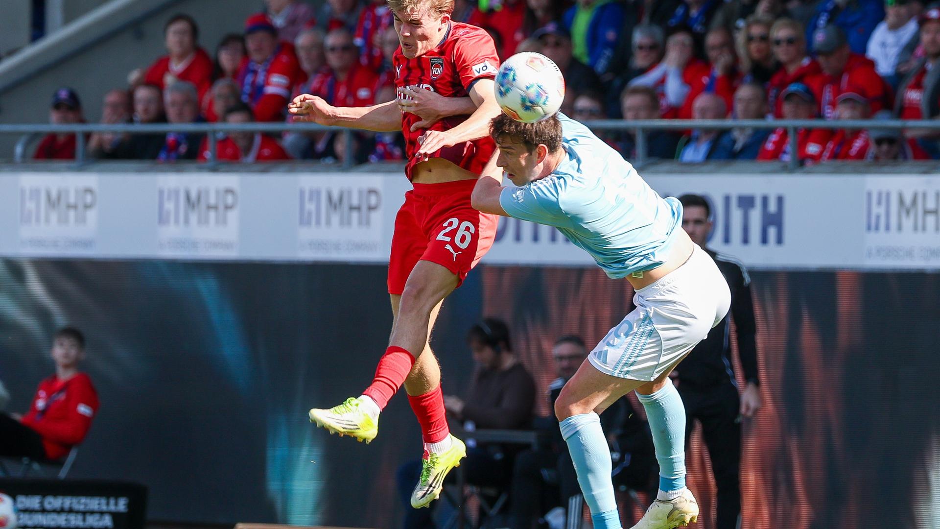 Hennes Behrens (Heidenheim) und Janik Haberer (Union Berlin) schweben beide in der Luft und versuchen, den Ball mit dem Kopf zu treffen.