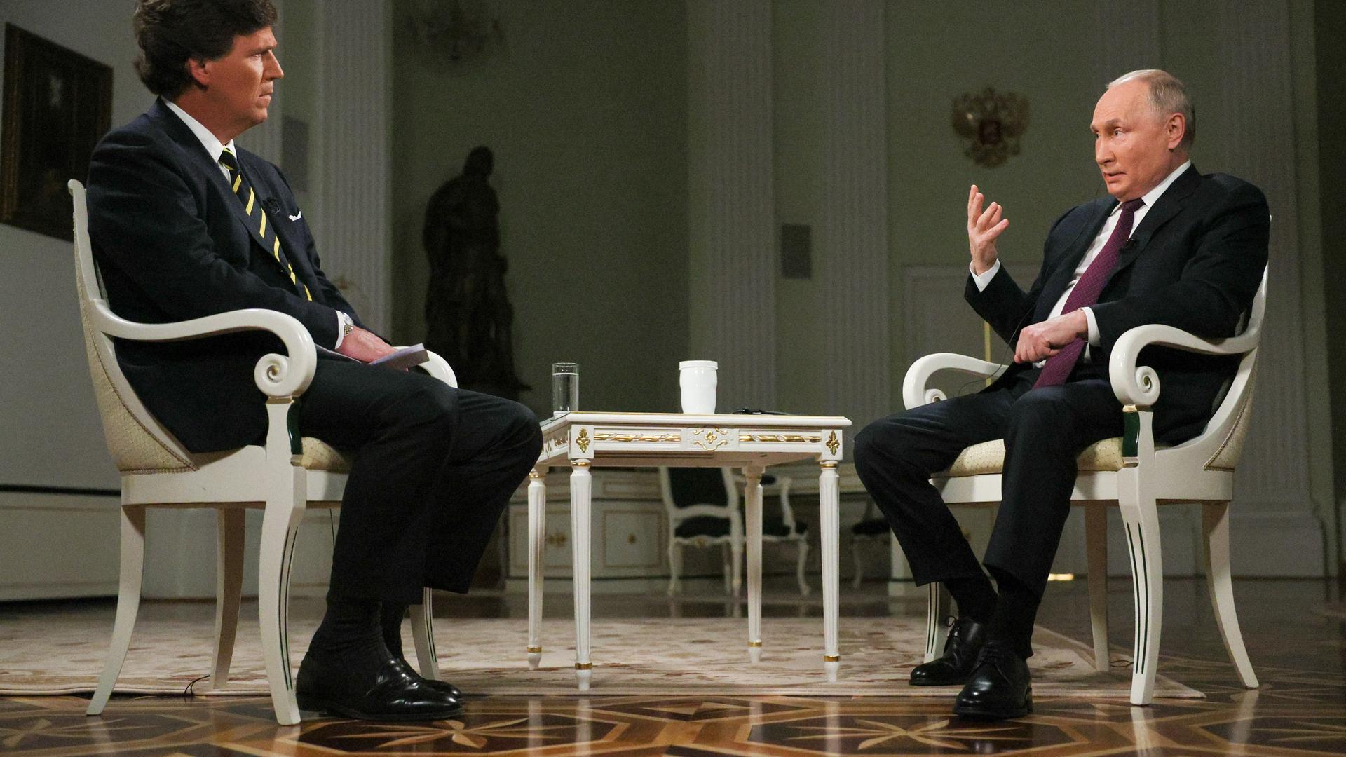 Tucker und Putin sitzen sich während des Interviews gegenüber