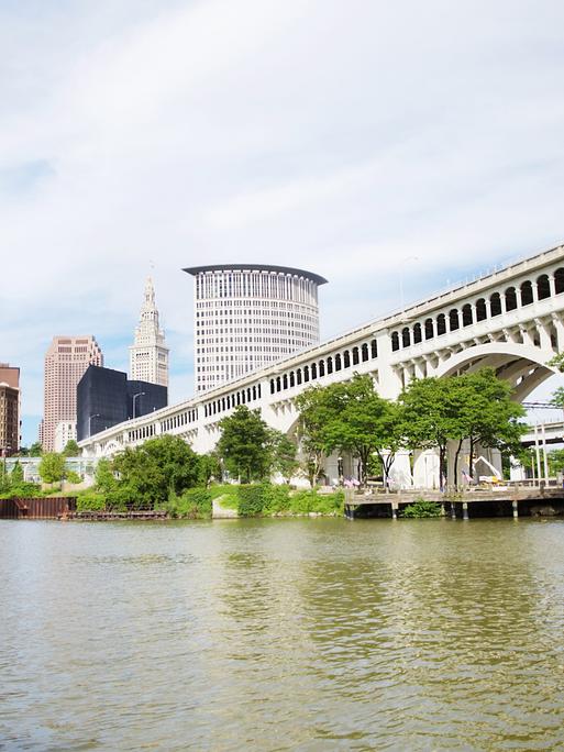 Die Skyline von Cleveland in Ohio, vom Heritage Park aus gesehen mit Brücke übers Wasser und Bäumen