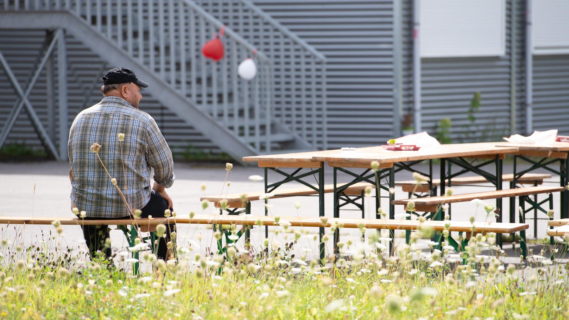 Ein Mann sitzt in Rückenansicht vor einer Flüchtlingsunterkunft in Bochum. 