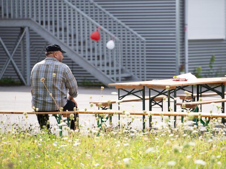 Ein Mann sitzt in Rückenansicht vor einer Flüchtlingsunterkunft in Bochum. 