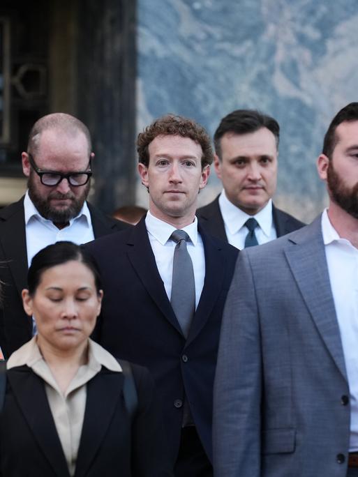 Meta-Ceo Mark Zuckerberg in einer Gruppe anderer Menschen in Business-Kleidung vor einem Gebäude