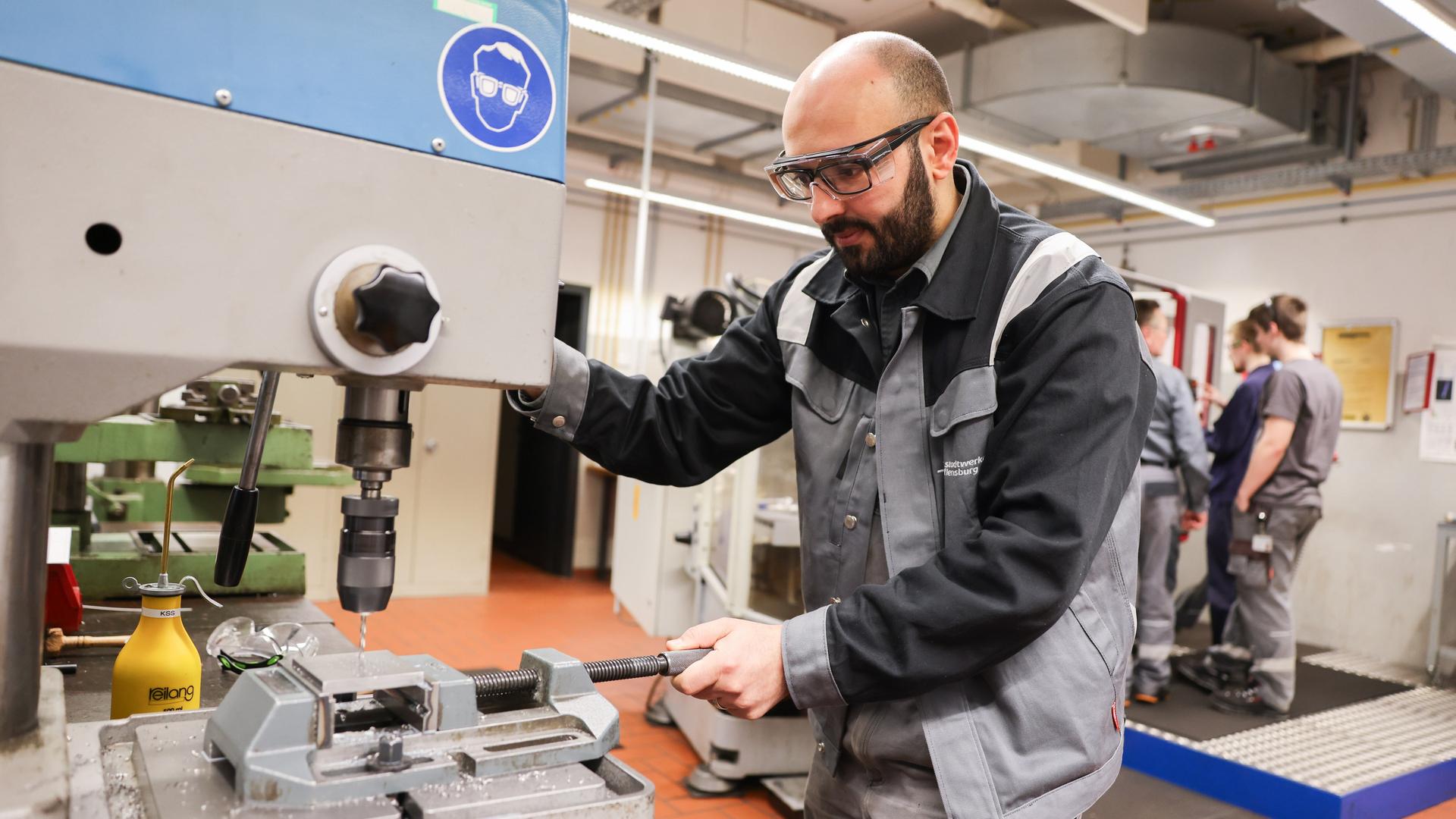 Ein Mensch mit Schutzbrille arbeitet an einer Maschine.