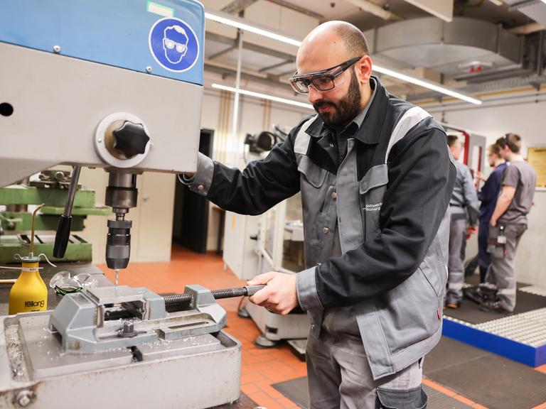 Ein Mensch mit Schutzbrille arbeitet an einer Maschine.
