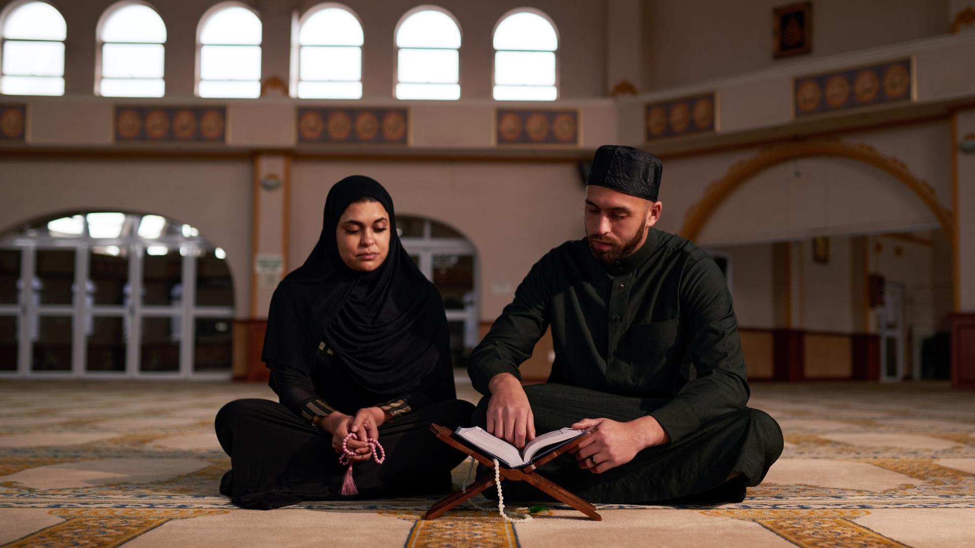 Ein junges Paar liest beim Gebet in einer Moschee im Koran.
