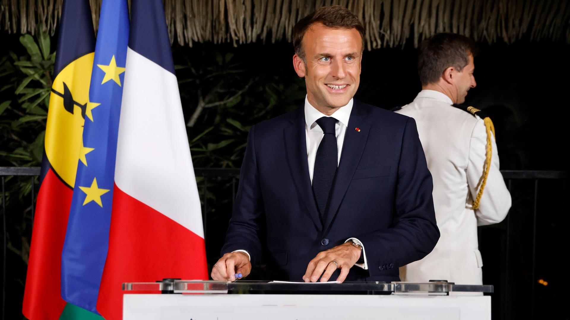 Frankreichs Präsident Emmanuel Macron lächelt während einer Rede in Neukaledonien in die Kamera.