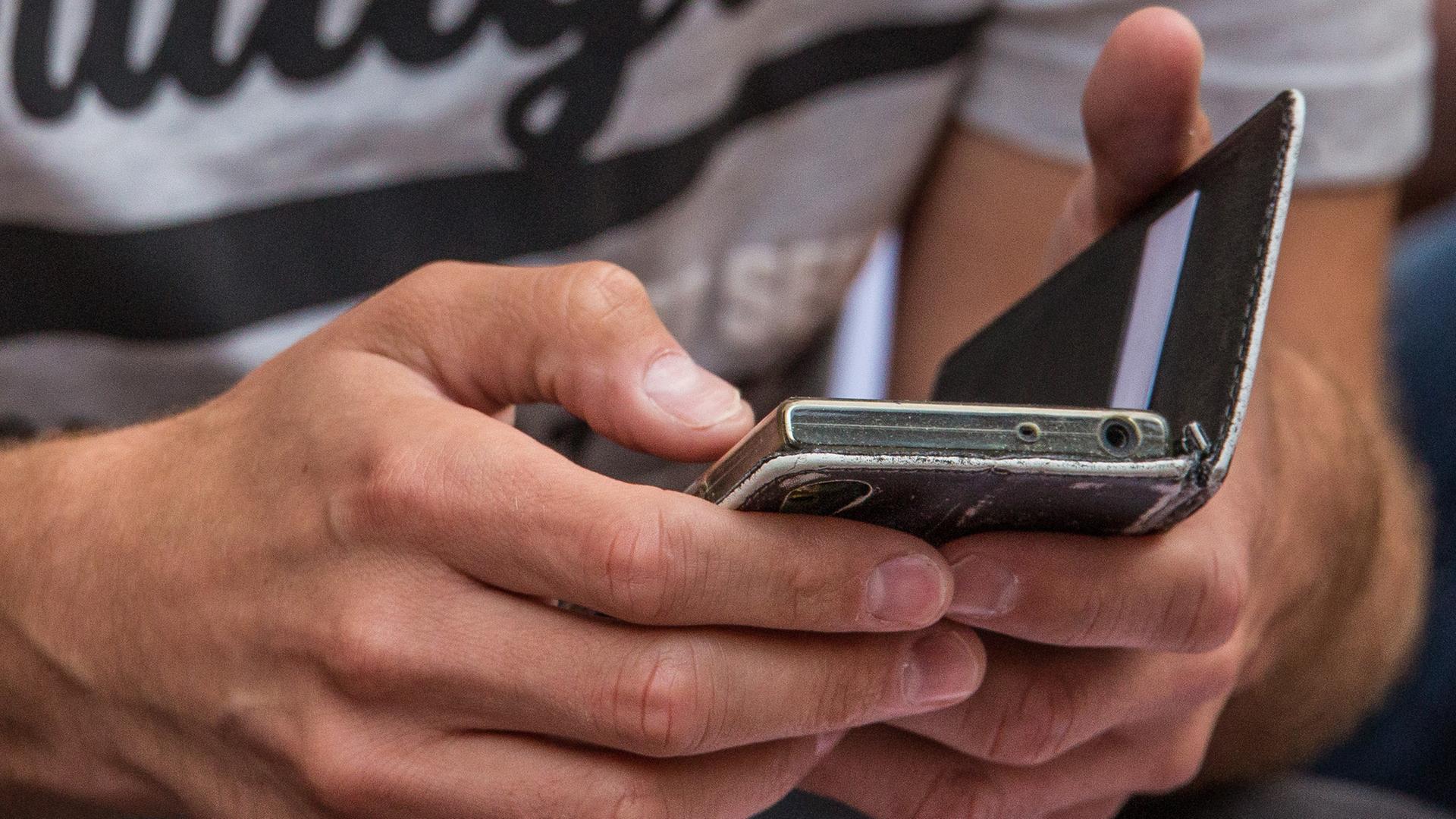 Ein Mann hält sein Smartphone in den Händen. 