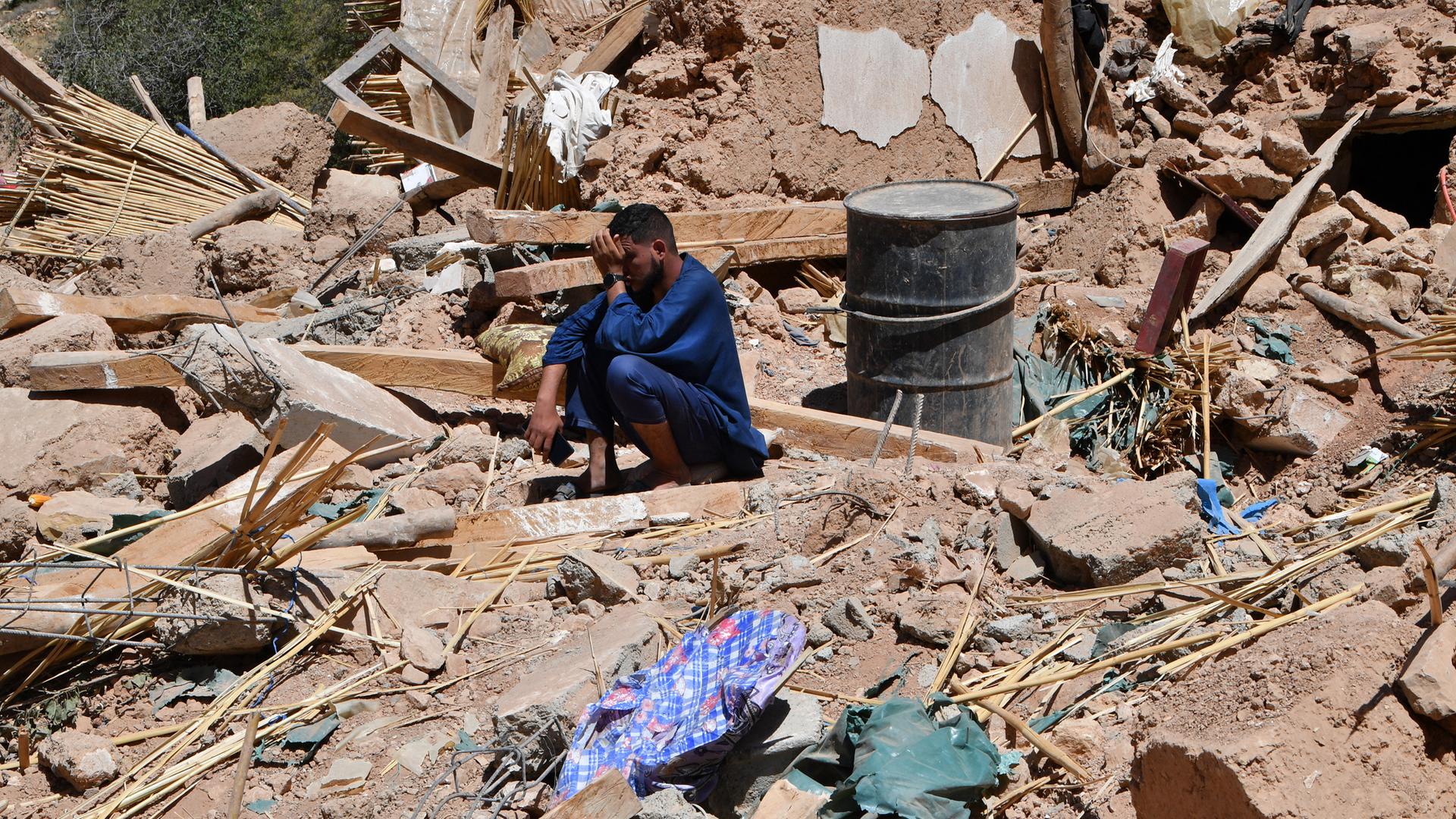 Ein Mann sitzt inmitten von Trümmern und weint.