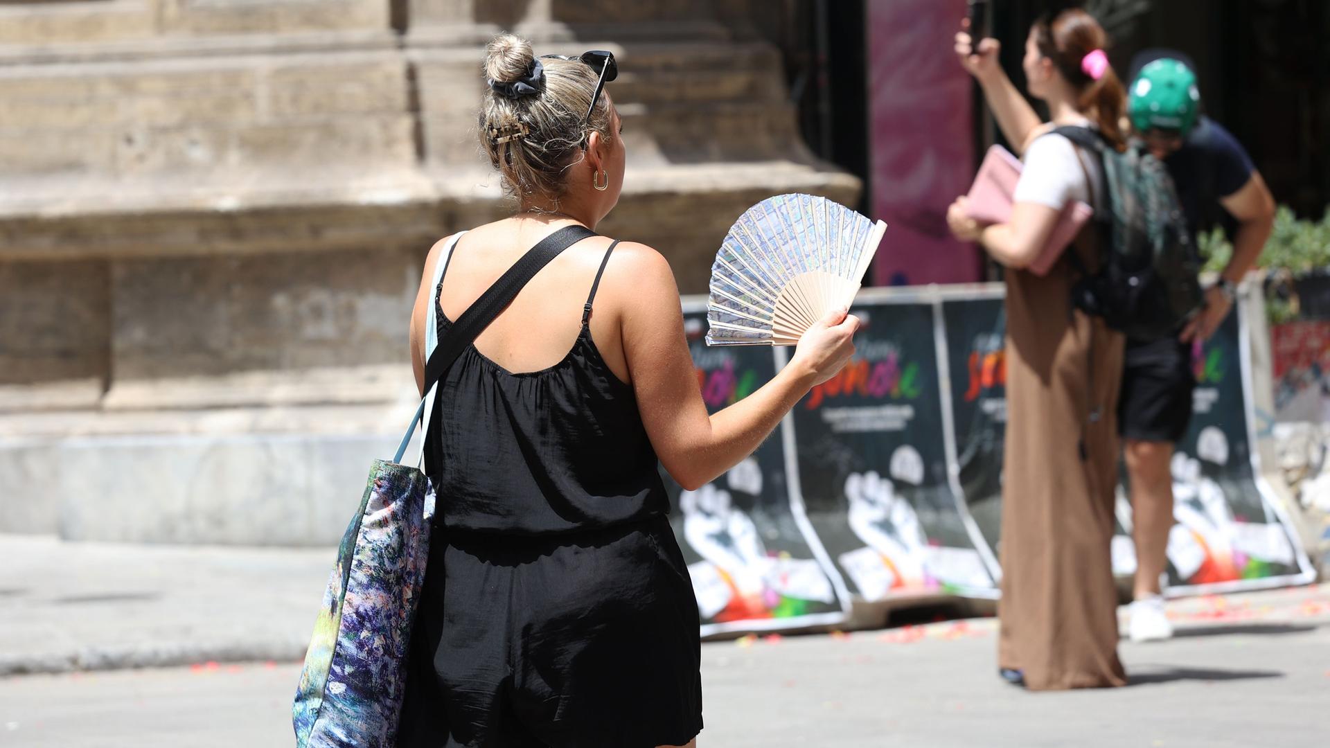 Italien, Palermo: Eine Frau benutzt ihren Fächer während der Hitze. Italien, Palermo: Eine Frau benutzt ihren Fächer während der Hitze.
