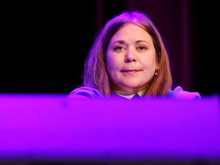 Eine junge Frau mit schulterlangen rötlich-hellbraunen Haaren sitzt auf einem Podium. Es ist die österreichische Autorin Stefanie Sargnagel.