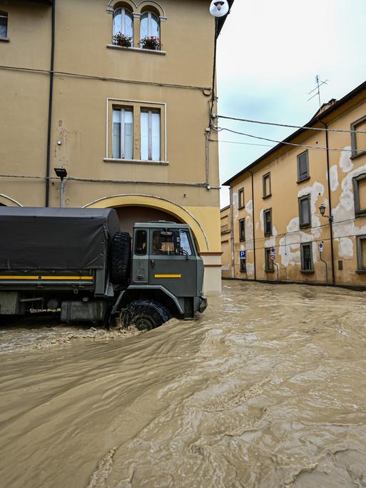 Ein dunkler Lkw fährt in einer Stadt durch überschwemmte Straßen