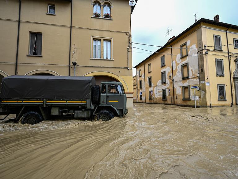 Ein dunkler Lkw fährt in einer Stadt durch überschwemmte Straßen