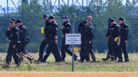 Einsatzkräfte der Polizei durchsuchen das Gelände abseits der Landebahn Nord auf dem Gelände des Flughafens Leipzig/Halle. Nach dem Drohnenvorfall in der Nacht zum Mittwoch laufen die Ermittlungen.