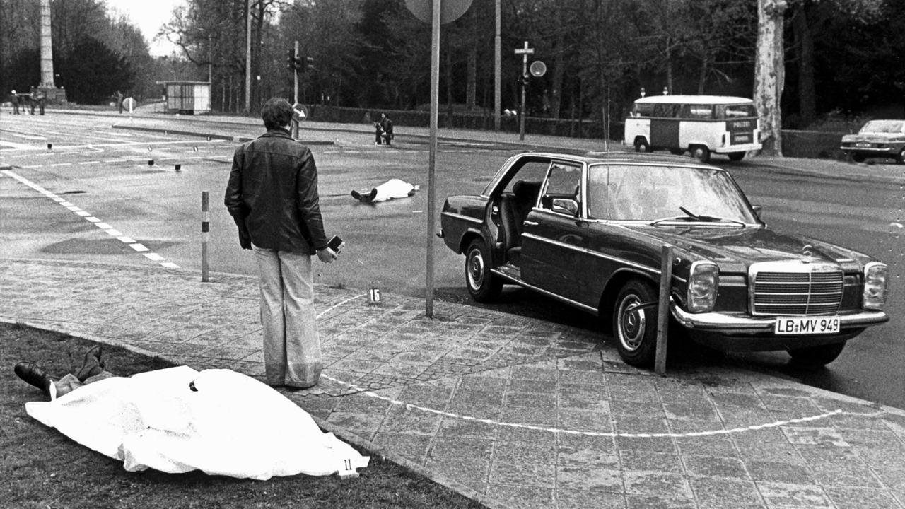Der Tatort mit den zugedeckten Leichen von Siegfried Buback (vorne links) und seines Fahrers Wolfgang Göbel sowie der Dienstwagen des Generalbundesanwaltes, in dem die beiden erschossen wurde. Deutschlands höchster Ankläger Siegfried Buback wurde am 7. April 1977 in Karlsruhe bei einem Anschlag der Rote-Armee-Fraktion (RAF) getötet. 