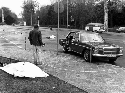 Der Tatort mit den zugedeckten Leichen von Siegfried Buback (vorne links) und seines Fahrers Wolfgang Göbel sowie der Dienstwagen des Generalbundesanwaltes, in dem die beiden erschossen wurde. Deutschlands höchster Ankläger Siegfried Buback wurde am 7. April 1977 in Karlsruhe bei einem Anschlag der Rote-Armee-Fraktion (RAF) getötet. 
