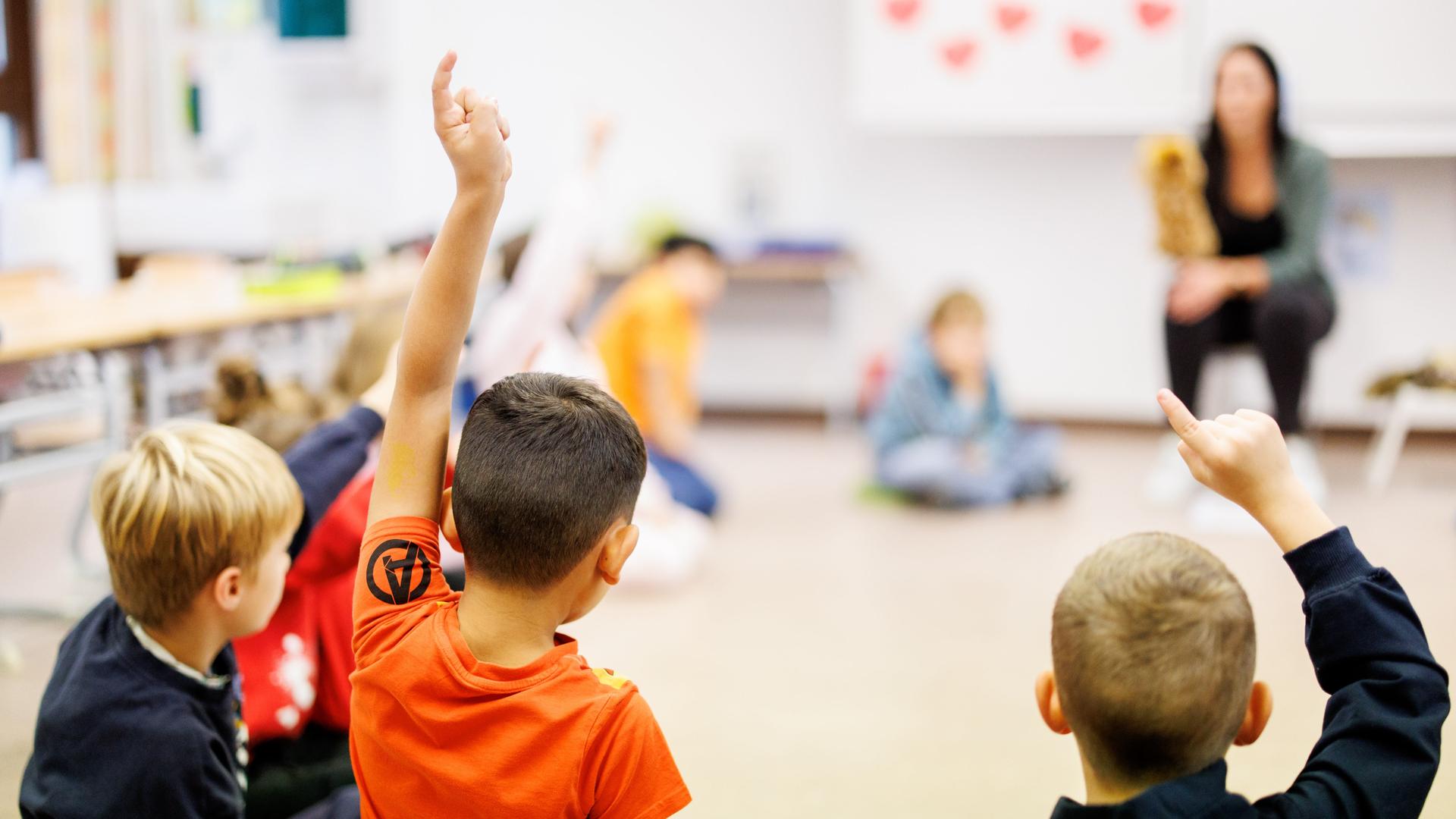 Schüler einer zweiten Klasse einer Grundschule im Stadtteil Neuperlach in München sitzen während des Unterrichts in einem Kreis auf dem Boden des Klassenzimmers zusammen und melden sich.