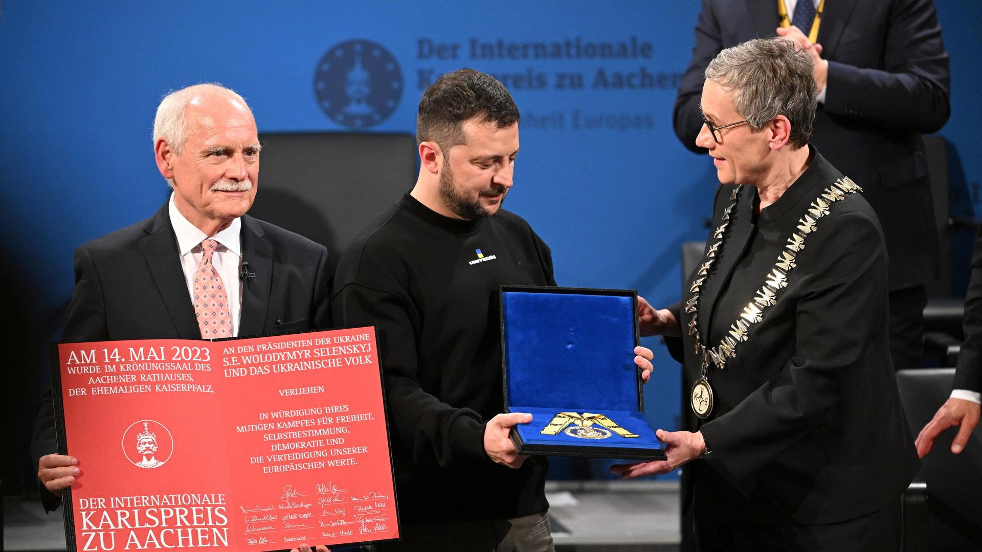 Verleihung des Internationalen Karlspreises in Aachen: Der ukrainische Präsident Wolodymyr Selenskyj (M.) erhält die Medaille aus den Händen von Aachens Oberbürgermeisterin Sibylle Keupen (r.).