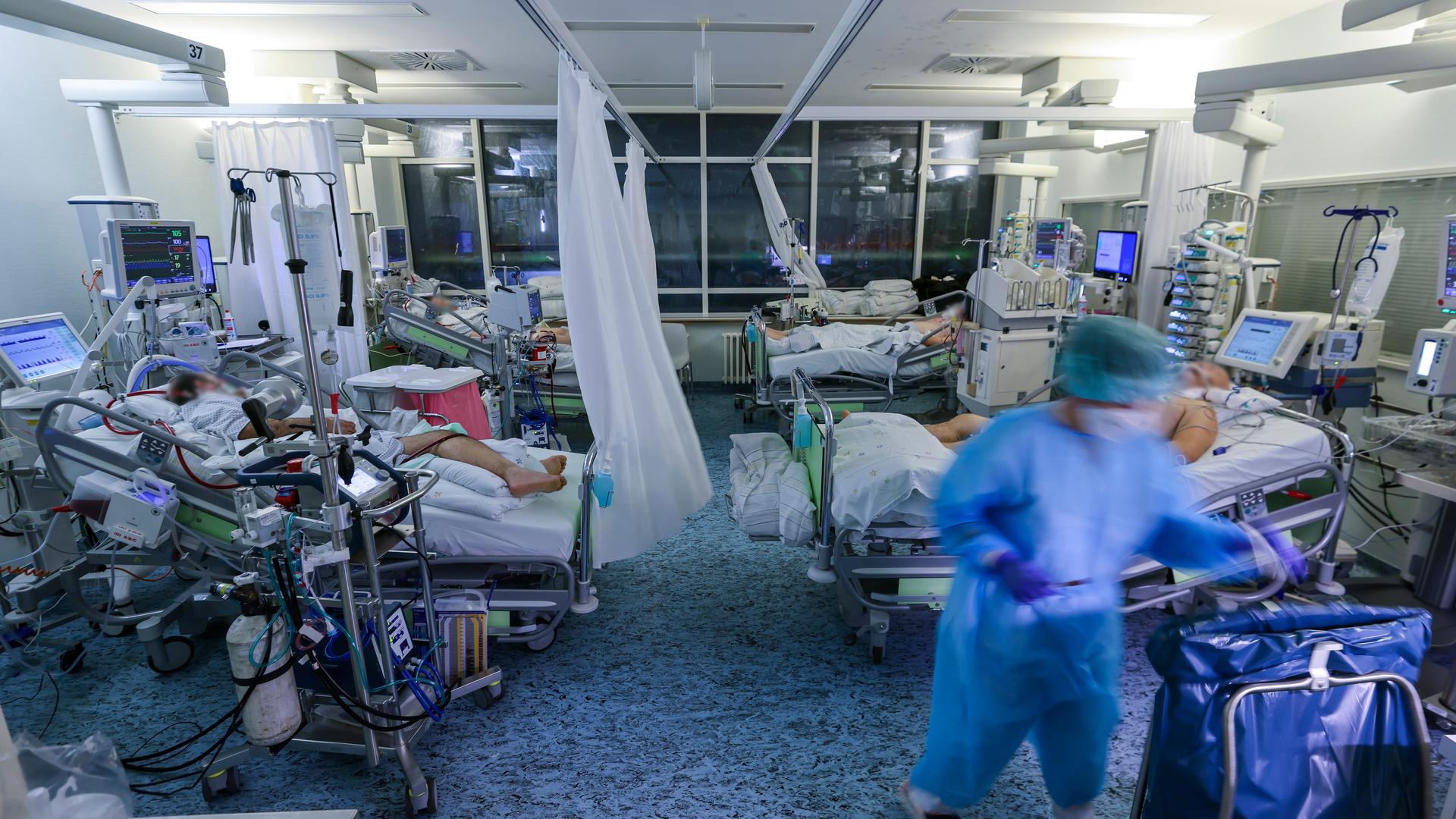 Eine Intensivpflegerin versorgt einen Covid-19-Patienten auf einer Intensivstation der Leipziger Uniklinik in einem Zimmer, in dem noch drei weitere Corona-Patienten liegen. Eine Intensivpflegerin versorgt einen Covid-19-Patienten auf einer Intensivstation der Leipziger Uniklinik in einem Zimmer, in dem noch drei weitere Corona-Patienten liegen.