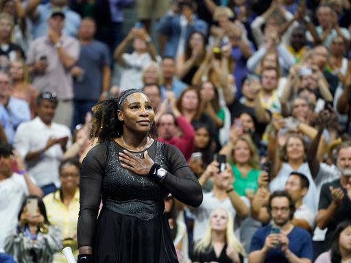 Serena Williams legt sich die Hand auf den Brustkorb und blickt in das Publikum der US Open.