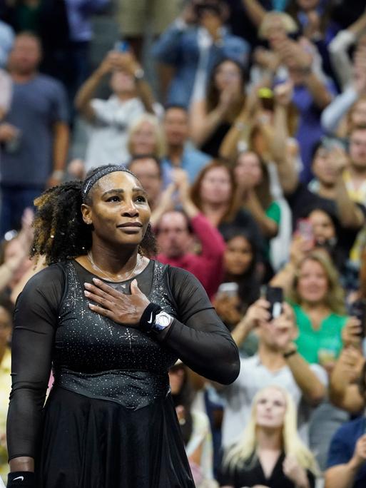 Serena Williams legt sich die Hand auf den Brustkorb und blickt in das Publikum der US Open.