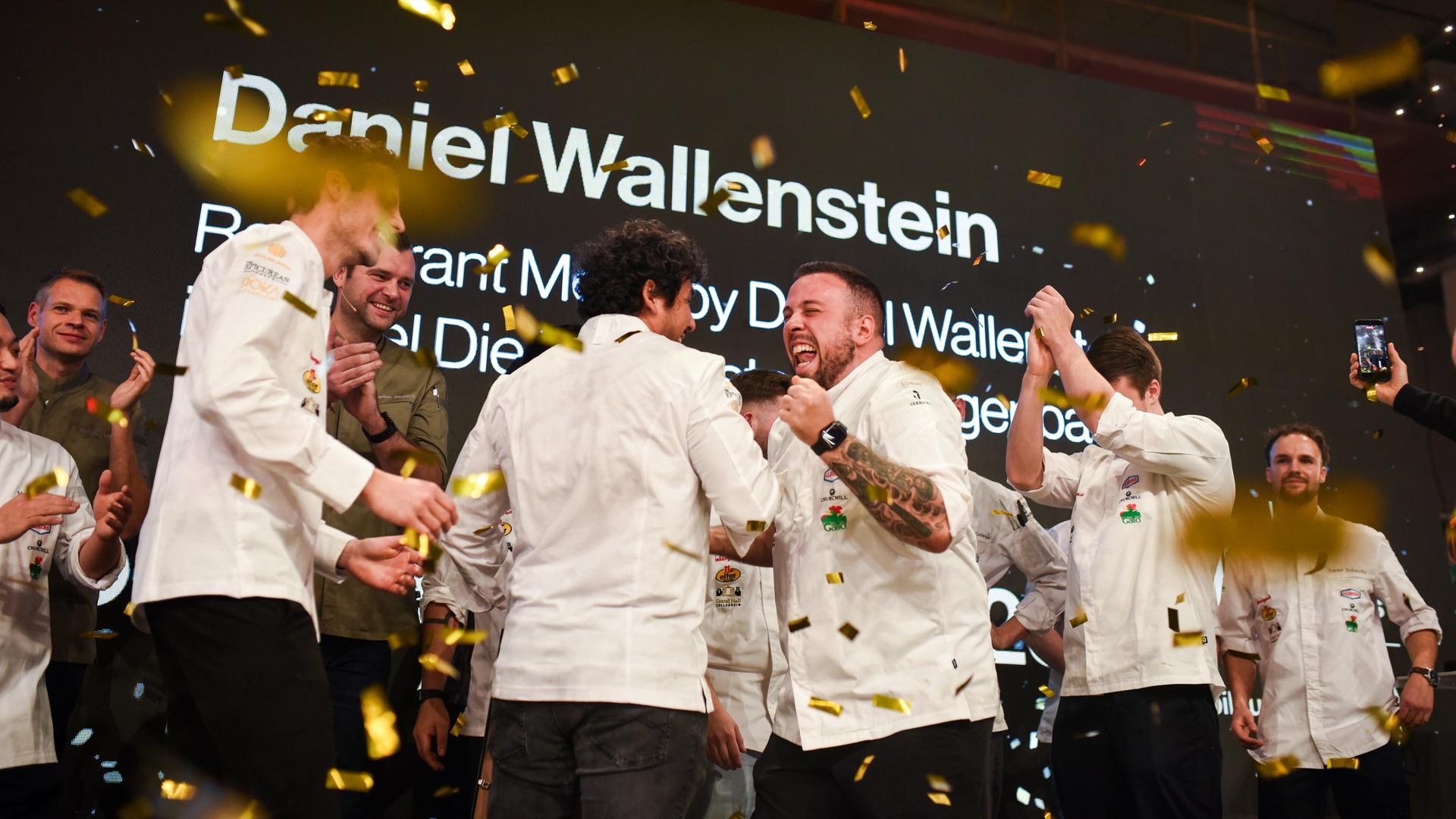 Daniel Wallenstein (M) feiert den Sieg als "Koch des Jahres" 2025. Er jubelt mit anderen Mitkonkurrenten.