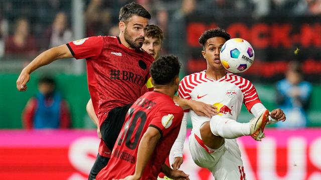 Das Foto zeigt mehrere Fußballer in roten und weißen Trikots. Sie kämpfen um den Ball.