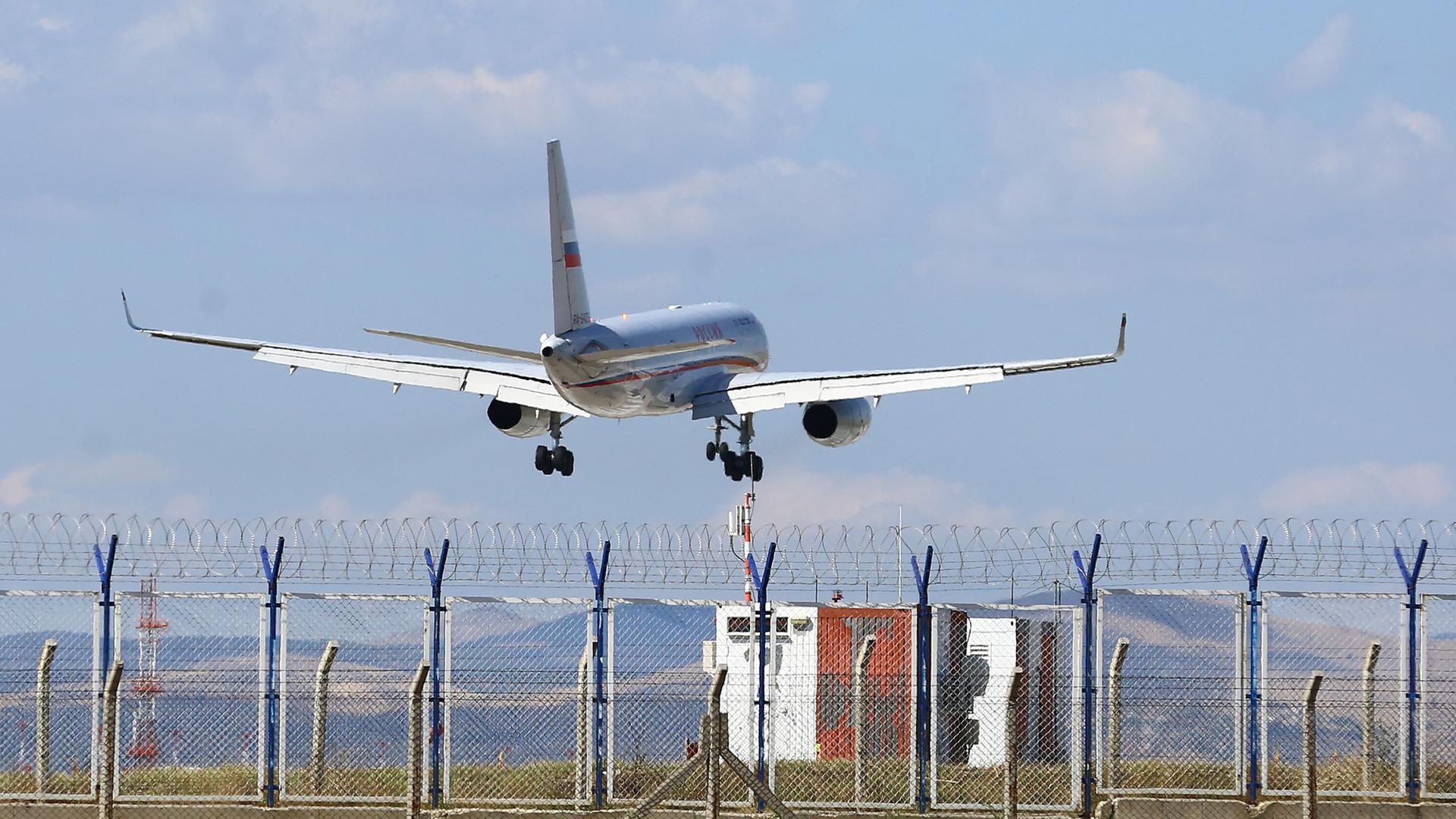 Ein Flugzeug mit russischen Fahnen auf den Flügeln landet auf einem Flughafen.