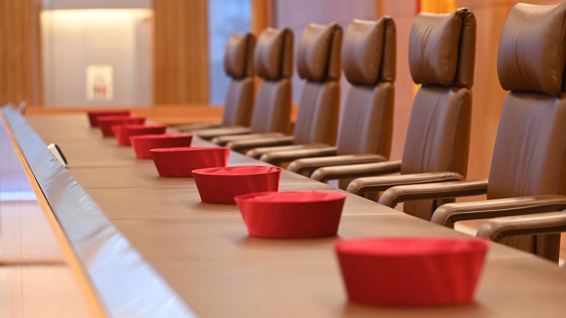 Auf der Richterbank im Sitzungssaal im Bundesverfassungsgericht liegen Barette der Bundesverfassungsrichter des ersten Senats. Auf der Richterbank im Sitzungssaal im Bundesverfassungsgericht liegen Barette der Bundesverfassungsrichter des ersten Senats.