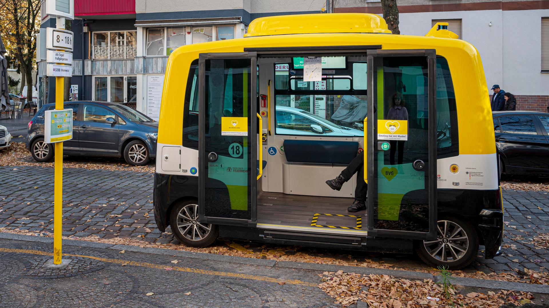 Ein autonomer Testbus der Berliner Verkehrsbetriebe mit geöffneter Tür an einer Haltestelle.