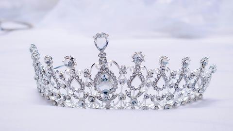 Auf einer edlen Tischdecke liegt eine Krone, die viele Kristalle gefasst hat.
