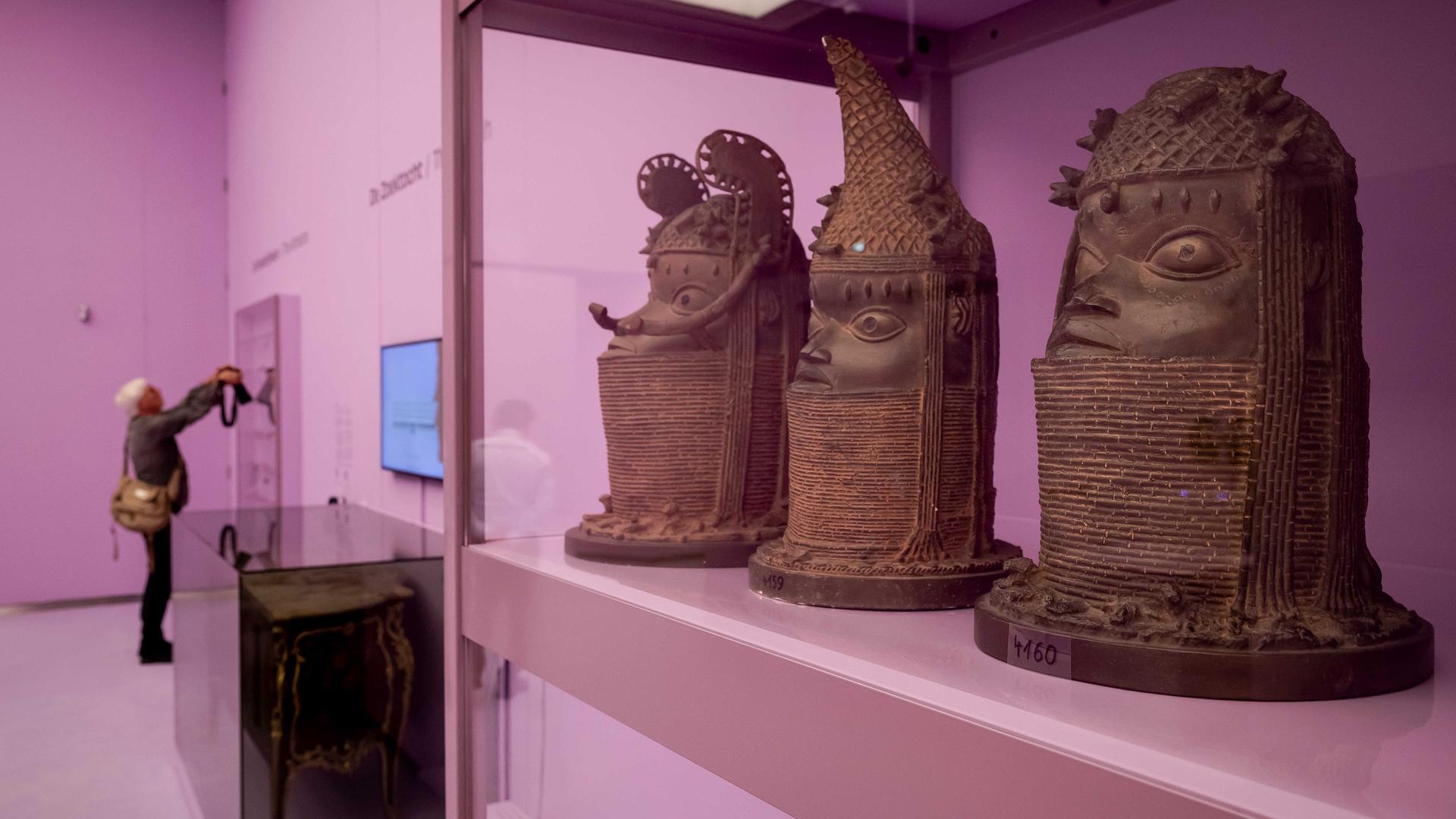 Abgüsse der Benin-Bronzen stehen in einem pinken Schaukasten in einem Museum in Den Haag