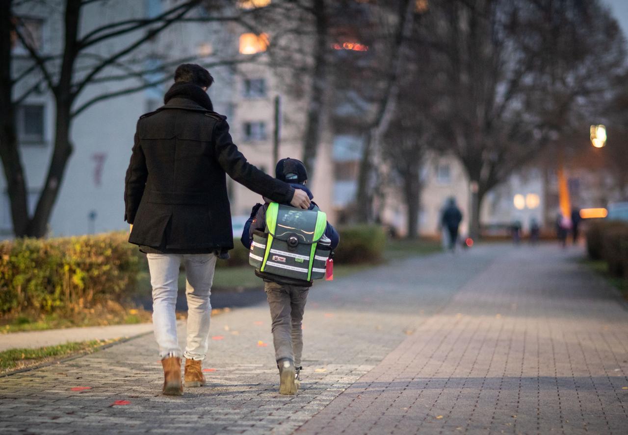 Ein Vater begleitet seinen Sohn auf dem Schulweg.