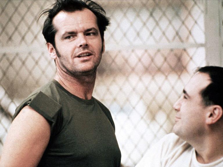 Filmszene aus "Einer flog über das Kuckucksnest" mit Jack Nicholson (links) und Danny DeVito (rechts), beide stehen vor einem Maschendrahtzaun Filmszene aus "Einer flog über das Kuckucksnest" mit Jack Nicholson (links) und Danny DeVito (rechts), beide stehen vor einem Maschendrahtzaun