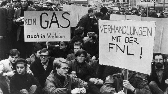 Ein Schwarz-Weiß-Foto mit Demonstierenden; auf ihren Transparenten steht "Kein Gas - auch in Vietnam" und "Verhandlungen mit der FNL!"