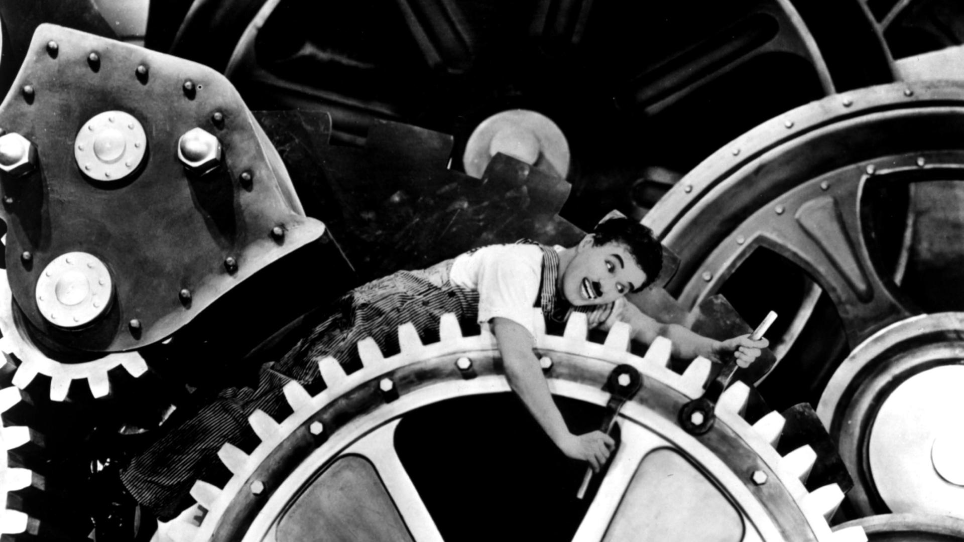 Filmszene aus dem Klassiker Modern Times von 1936. Charlie Chaplin gerät ins Räderwerk der modernen Industrie- und Massengesellschaft.