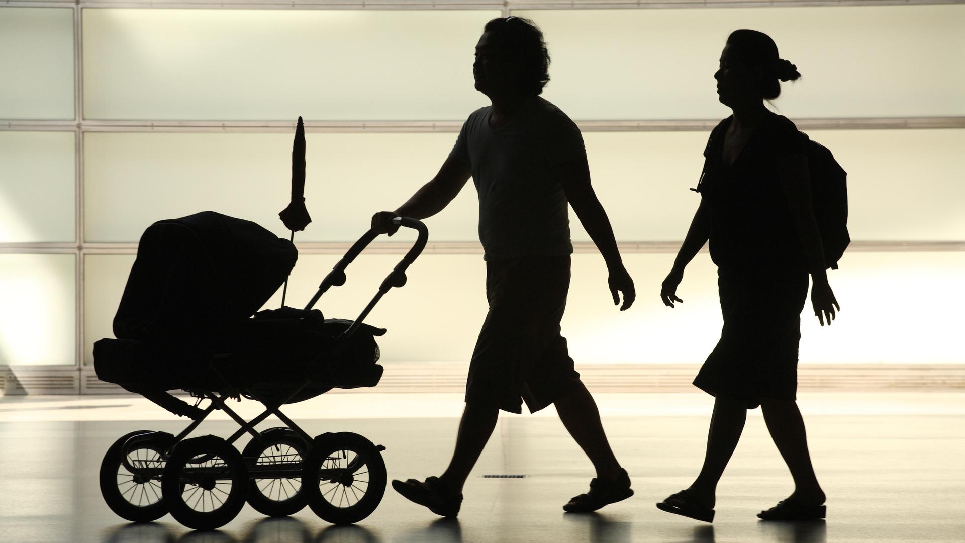 Silhouette einer Kleinfamilie mit Kinderwagen Silhouette einer Kleinfamilie mit Kinderwagen
