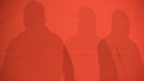 Schatten von drei Personen auf einer roten Wand. Landesparteitag der Partei Die Linke in Berlin.