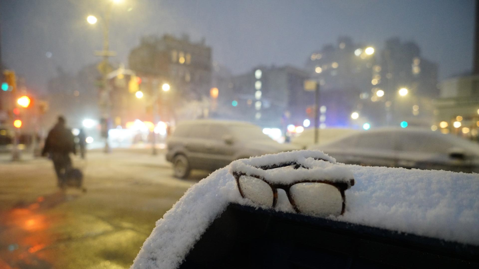 Eine Brille liegt während eines Schneesturms im Schnee auf einem Briefkasten. 