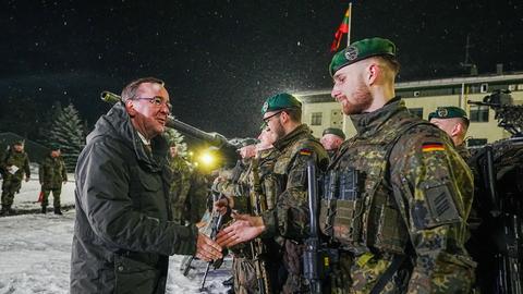 Bundesverteidigungsminister steht vor Bundeswehrsoldaten des deutschen Einsatzkontingents in Litauen. Einem Soldaten schüttelt er die Hand.