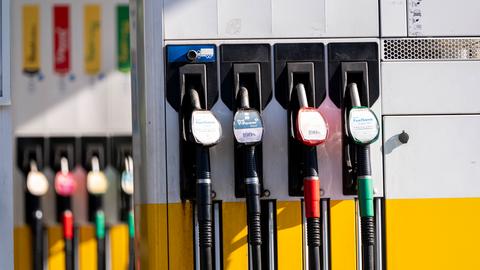 Das Bild zeigt mehrere Zapfsäulen an einer Tankstelle. Im Vordergrund sind vier Zapfpistolen zu sehen, daneben weitere unscharf im Hintergrund.