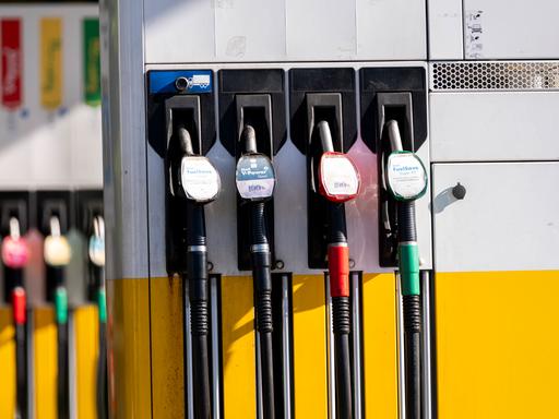 Das Bild zeigt mehrere Zapfsäulen an einer Tankstelle. Im Vordergrund sind vier Zapfpistolen zu sehen, daneben weitere unscharf im Hintergrund.