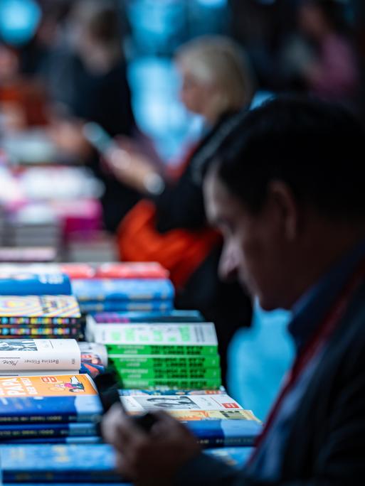 Ein Tisch mit Büchern und ein Mann, der sich darüber beugt. Ein Tisch mit Büchern und ein Mann, der sich darüber beugt.