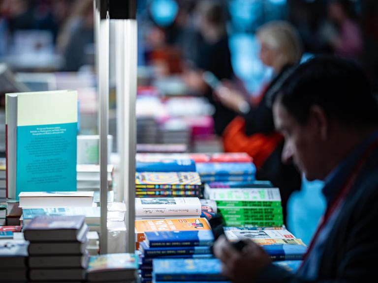 Ein Tisch mit Büchern und ein Mann, der sich darüber beugt. Ein Tisch mit Büchern und ein Mann, der sich darüber beugt.