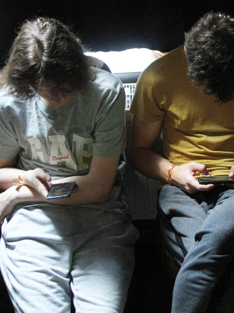 Junge Leute sitzen mit Smartphones da und spielen oder surfen