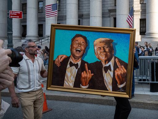 Inmitten von Demonstranten, die am Foley Square in New York gegen die Politik von Donald Trump in Bezug auf Zölle, Arbeitnehmerrechte und Bürgerrechte protestieren, ist ein Gemälde oder Kunstwerk mit den Figuren von Elon Musk und Trump zu sehen. 
