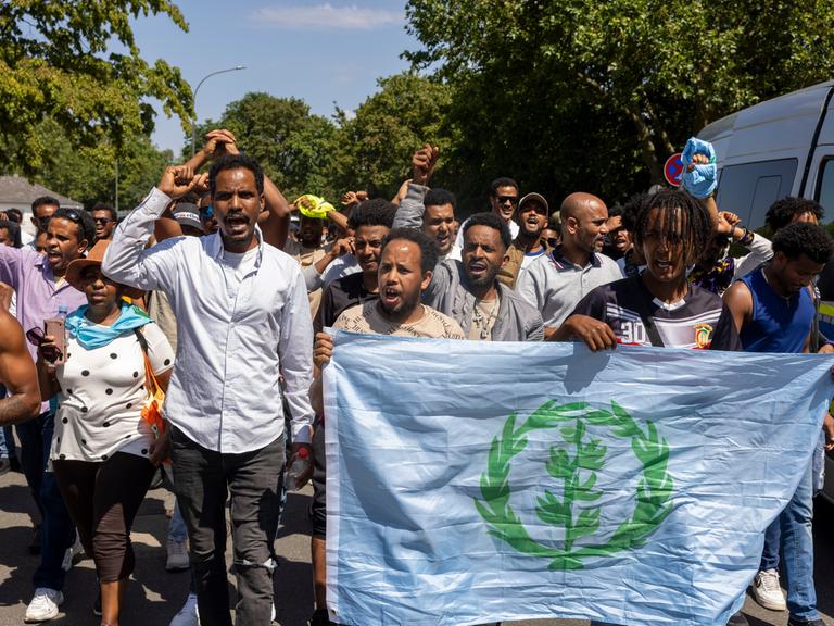 Teilnehmer der Demonstration gegen das Eritrea-Festival in Gießen gehen durch die Innenstadt. Nach den Ausschreitungen rund um das umstrittene Eritrea-Festival in Gießen hat sich die Lage nach Einschätzung der Polizei am Samstagnachmittag wieder etwas beruhigt, insgesamt seien im Tagesverlauf mehrere Hundert Personen kontrolliert worden. Die Polizei versuchte die Gegendemonstranten immer wieder vom Festival-Ort fernzuhalten, und hatte dazu berittene Polizei und Wasserwerfer vor Ort ohne sie aber einzusetzen.