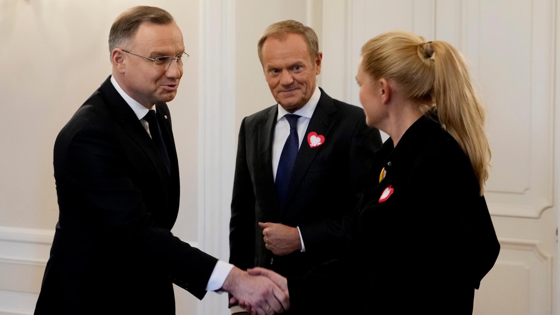 Polens Präsident Andrzej Duda (links) schüttelt der damaligen Oppositionspolitikerin Barbara Nowacka die Hand, während der damalige Oppositionsführer Donald Tusk (Mitte) am Dienstag, den 24. Oktober 2023, im Präsidentenpalast in Warschau, Polen, zuschaut. 