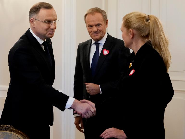 Polens Präsident Andrzej Duda (links) schüttelt der damaligen Oppositionspolitikerin Barbara Nowacka die Hand, während der damalige Oppositionsführer Donald Tusk (Mitte) am Dienstag, den 24. Oktober 2023, im Präsidentenpalast in Warschau, Polen, zuschaut. 