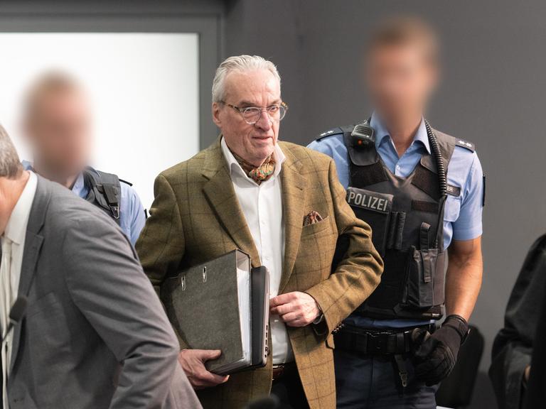 Der Hauptangeklagte Heinrich der XIII. Prinz Reuß (M) kommt von Polizisten gebracht in den Verhandlungssaal im Oberlandesgericht Frankfurt, Außenstelle im Stadtteil Sossenheim.